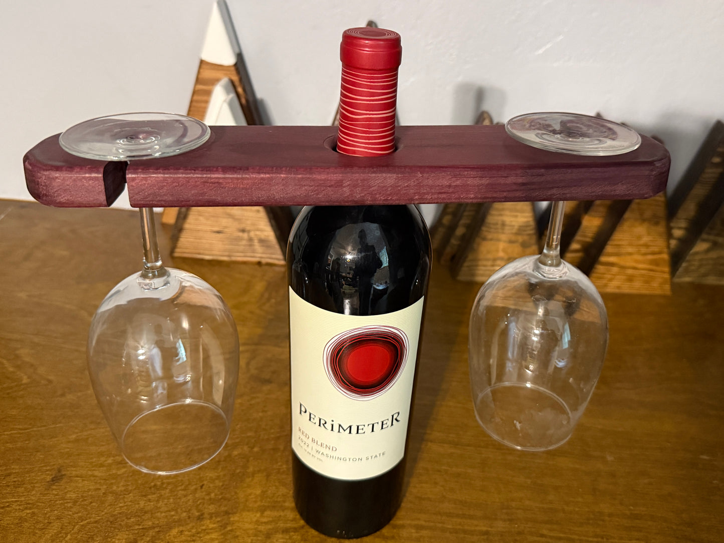 Wine bottle with a wooden holder and two glasses on a wooden surface